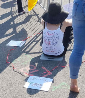 Frau sitzt auf einem Küchenschneidbrett im Sommershirt mit Aufschrift