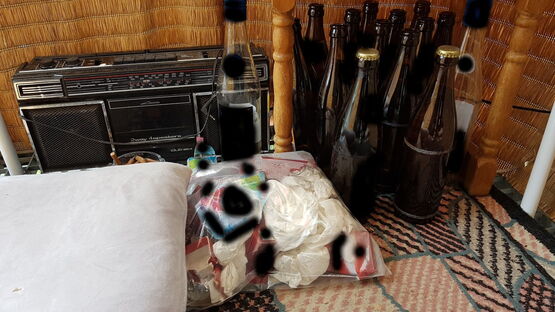 Ein altes Radio, elf leere Flaschen bir und zwei Volle, 2 leere Schnapsflaschen, eine Plastiktüte mit Rotzfahnen und ein voller Aschenbecher auf der Terrase