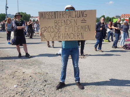 Die Sonnenbrille des Mannes lugt hinter dem Plakat hervor