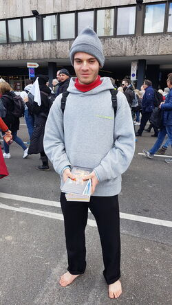 Junger Mann, barfuß, mit Flyern