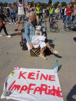 Frau mit kleinem weißen Hund auf dem Schoß ein großes weißes Leinentuch vor den Füßen