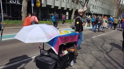 Frau mit Kinderwagen und weißem Sonnenschirm