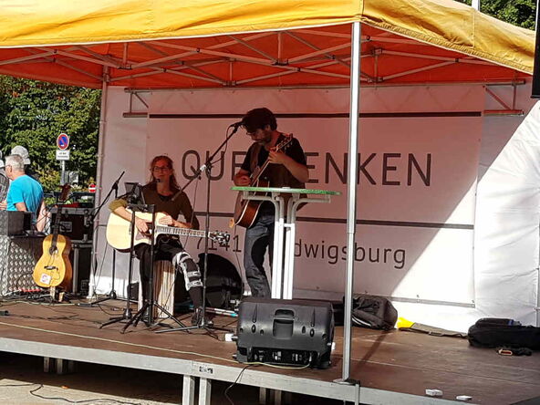 Ein Pärchen. Beider spielen Gitarre auf der Querdenken-Bühne