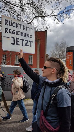 Mann hebt ein Plakat hoch (schwarz auf weiß)