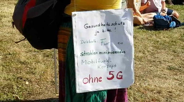 Frau in bunter Hose und gelbem Shirt mit weißem Plakat