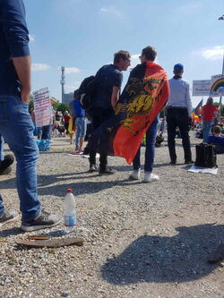 Teilnehmer*innen auf der Demo, darunter eine Person mit einem Umhang in Schwarz‑Weiß‑Rot und einem goldenen Adlermotiv.